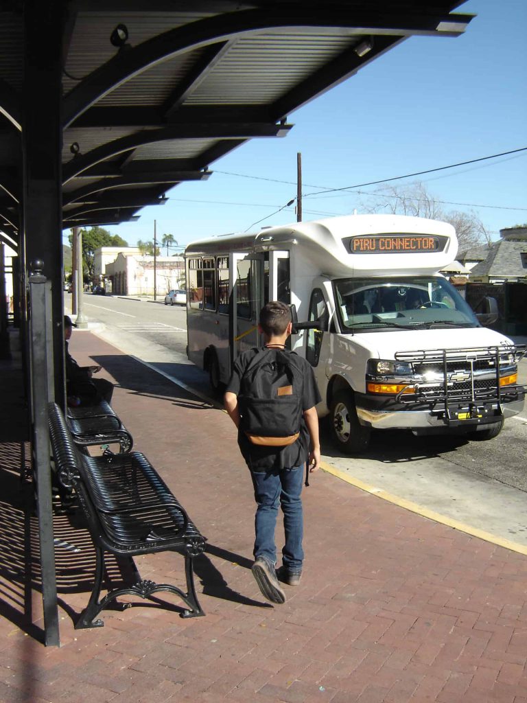 Man with backpack getting on Valley Express bus